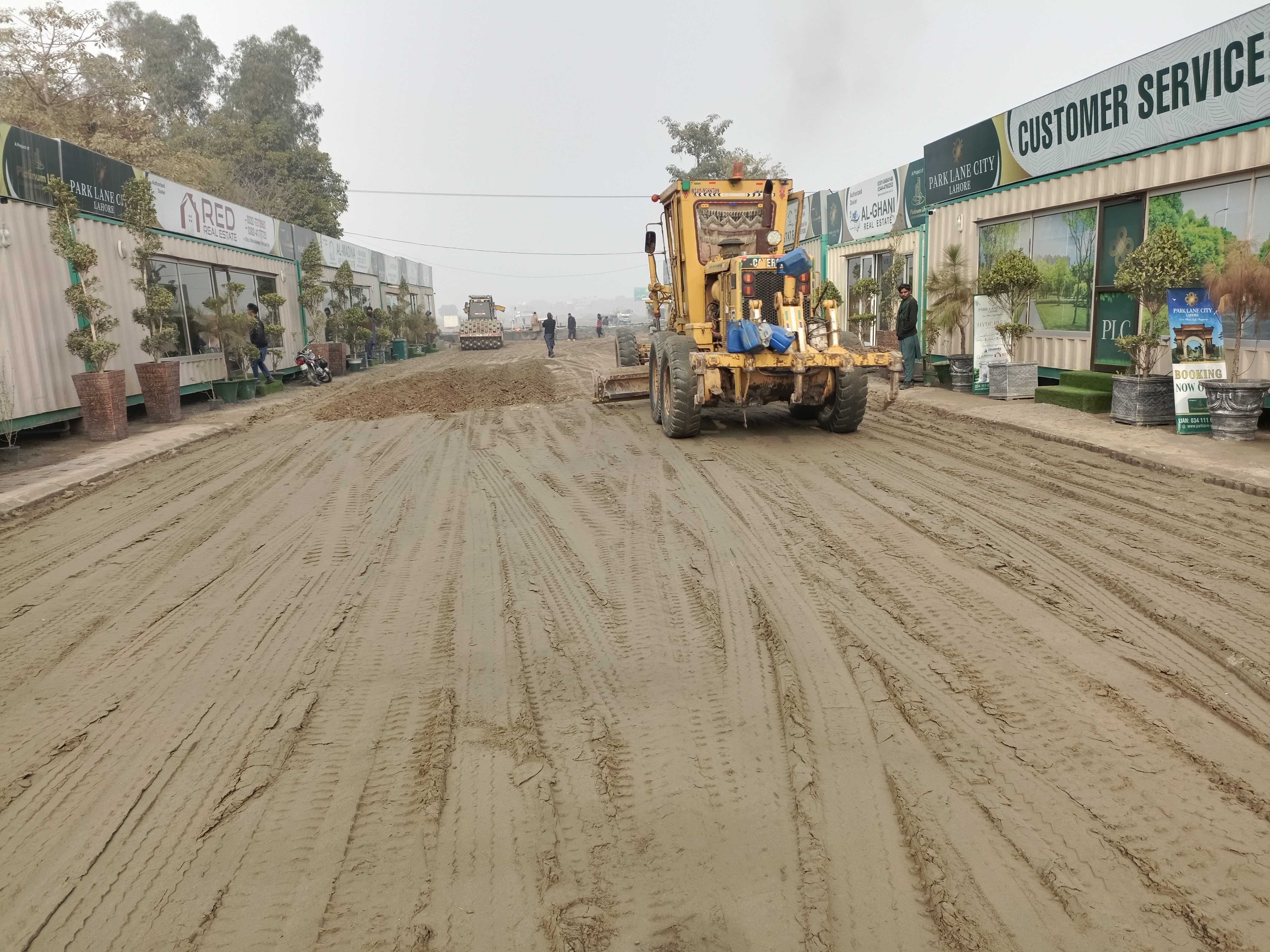 Road grader working on street with PLC Customer Service container office visible, January 2023